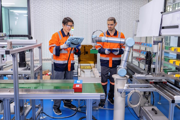 Engineers working on a cobot using a connected tablet