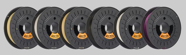 A row of different 3D printing filament spools